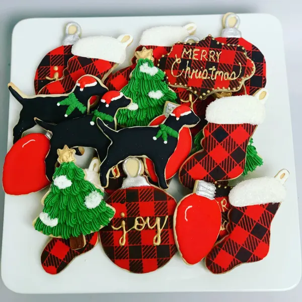 Christmas platter of buffalo plaid stockings and ornaments, black dogs in Santa hats and joy lettering