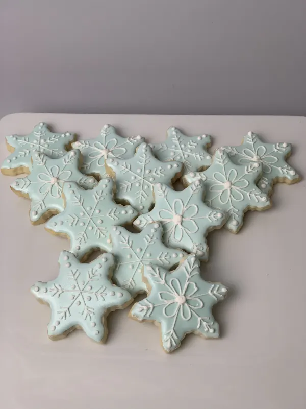 Pale aqua snowflake cookies with white piped crystal and flower detail on a white platter