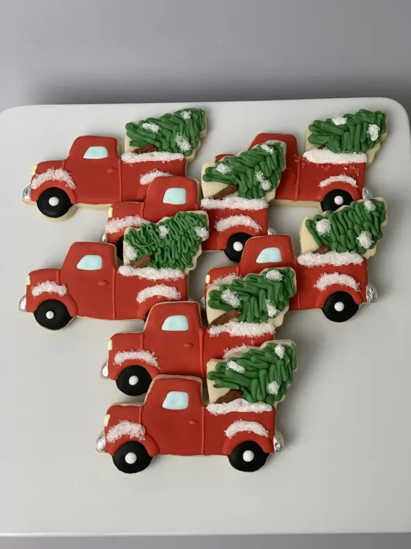 Nine red pickup truck cookies hauling piped green Christmas trees in the truck bed
