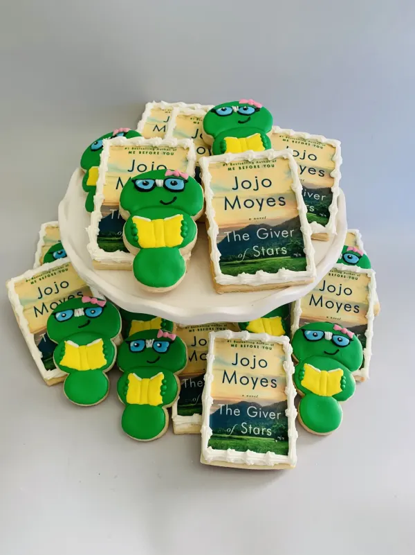 Cookies printed with the book cover The Giver of Stars plus green bookworm cookies