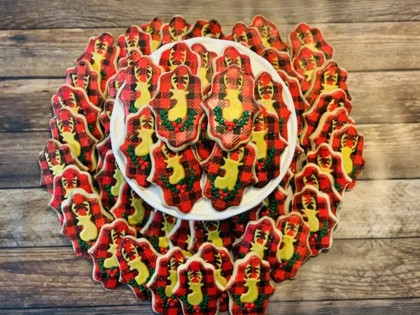 Red buffalo plaid cookies with a gold deer silhouette and green holly wreath