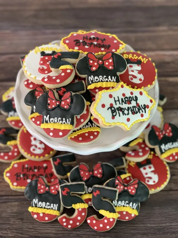Minnie Mouse cookies with red polka dot bows lettered Morgan, a number 5 and Happy Birthday