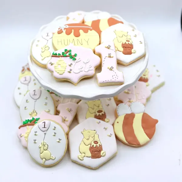 First birthday cookies with honey pots, a bear, bees, balloons and number one plaques