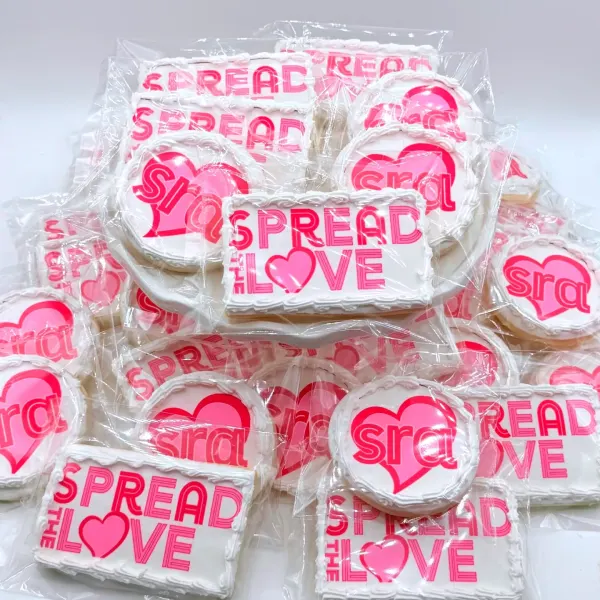 Individually wrapped pink cookies lettered Spread the Love with a round heart logo