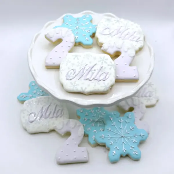 Snowflake cookies in blue and white with Mila plaques and number two cookies