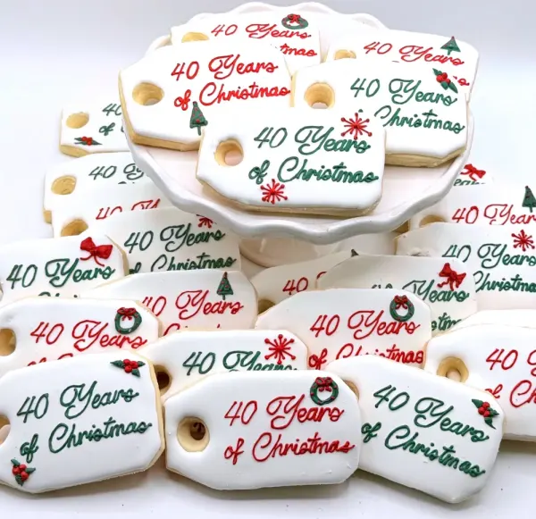 White plaque cookies lettered 40 Years of Christmas in red script with holly and small bows