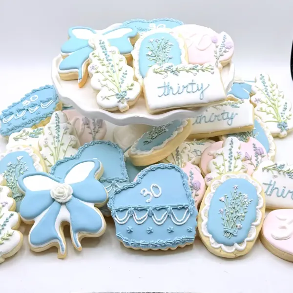 Blue and white thirtieth birthday cookies with bows, piped florals, lavender sprigs and thirty plaques