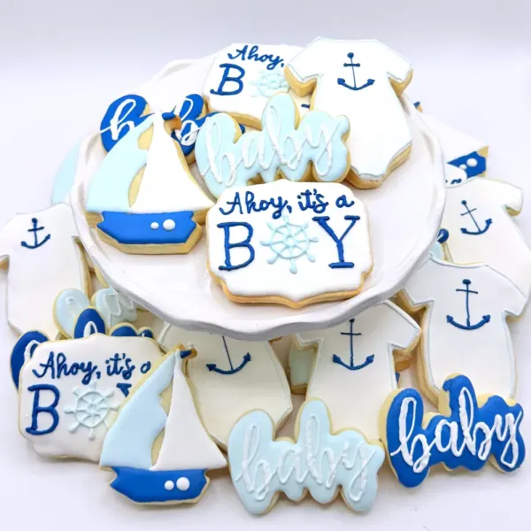 Blue nautical baby shower cookies with sailboats, anchors and Ahoy it's a boy lettering
