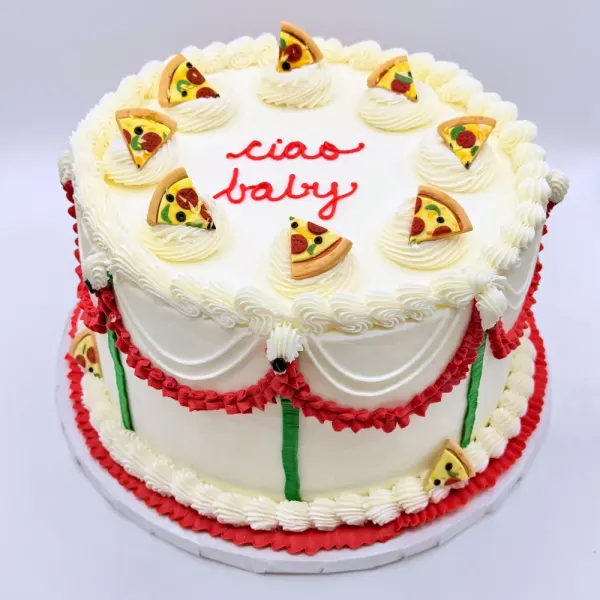 White cake with piped rosettes, pizza slice toppers and ciao baby in red script, with red and green swags