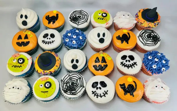 Halloween cupcakes iced as ghosts, black cats, spiderwebs, mummies, witch hats and monster eyes