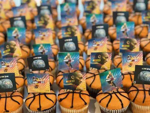 Basketball cupcakes in orange buttercream with black piped seams and NBA 2K24 card toppers