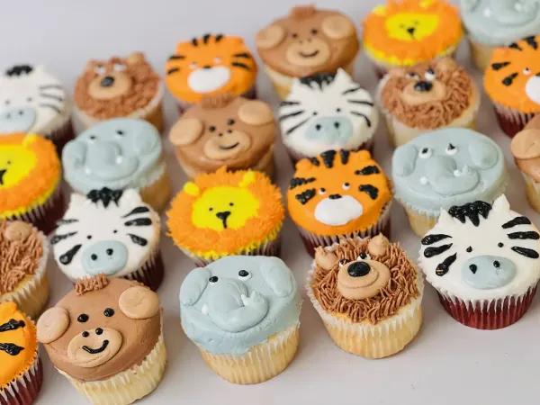 Safari animal cupcakes piped as lions, tigers, zebras, elephants, monkeys and bears