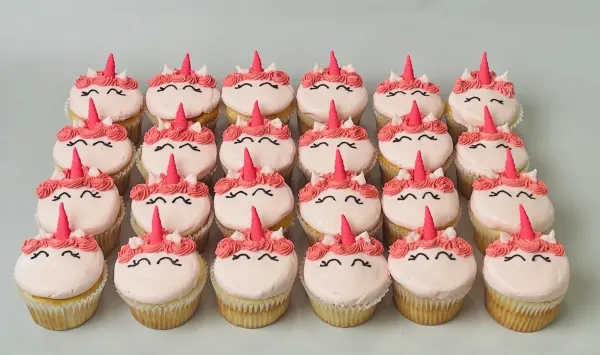 Unicorn cupcakes in pale pink buttercream with pink fondant horns and piped closed eyes