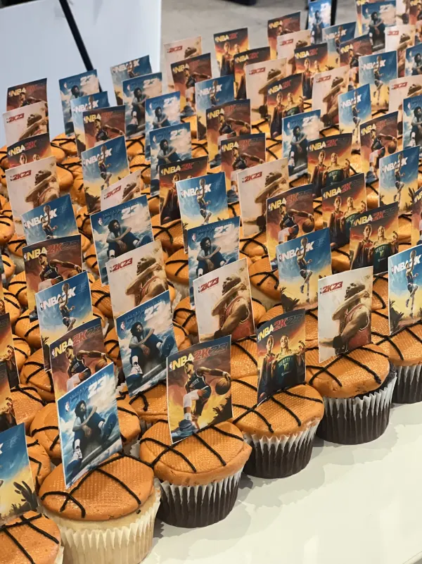 Basketball cupcakes with orange frosting, piped black seam lines and NBA 2K23 picture toppers