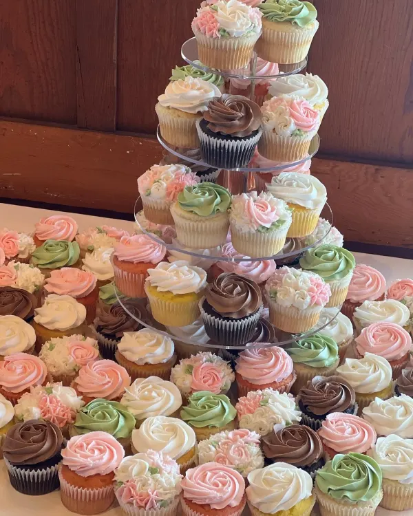 Tiered stand of buttercream rosette cupcakes in pink, white, green and chocolate
