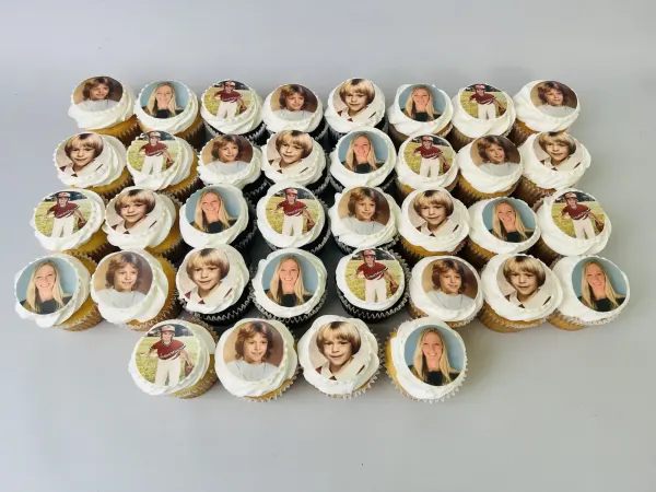 Tray of white-frosted cupcakes topped with edible photo prints of childhood portraits