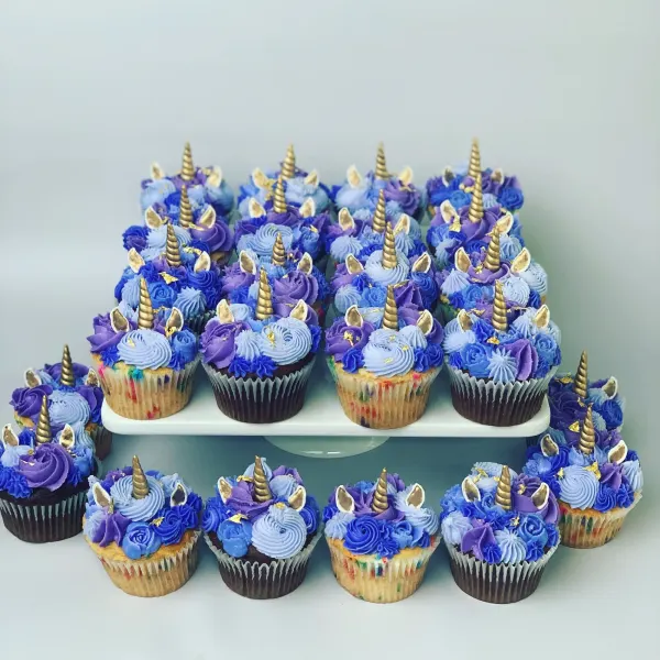 Unicorn cupcakes in blue and purple buttercream with gold fondant horns, ears and gold leaf