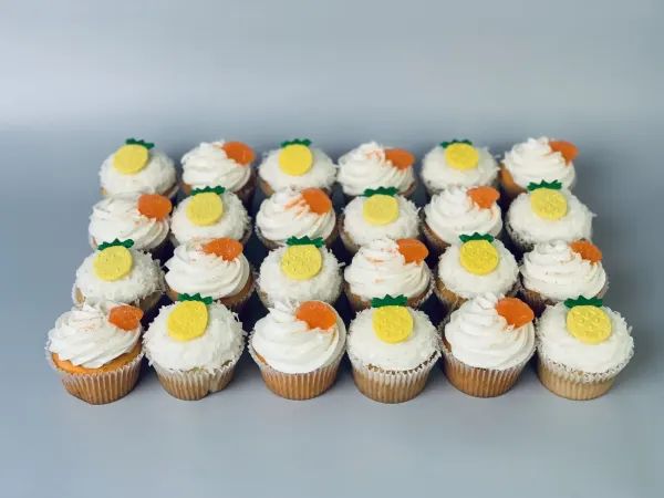 Cupcakes with coconut and white buttercream topped with fondant pineapples and orange slices