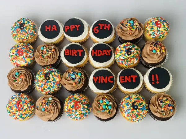 Sprinkle and chocolate buttercream cupcakes with discs reading HAPPY 6TH BIRTHDAY VINCENT
