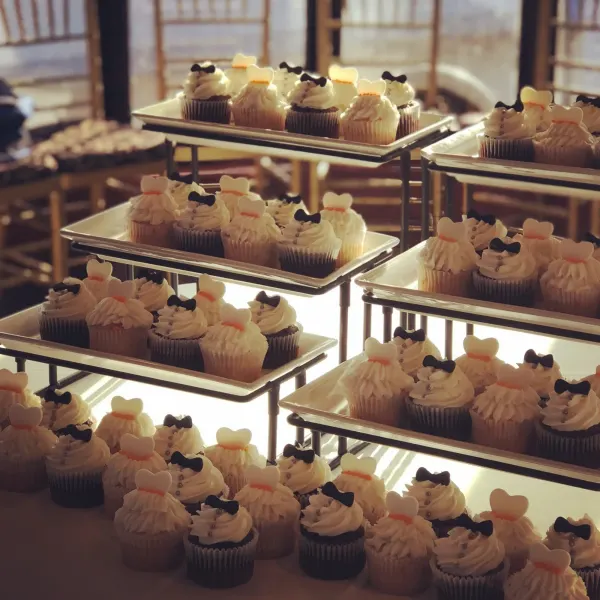 Wedding cupcakes piped as gowns with fondant bodices and as tuxedos with black bow ties