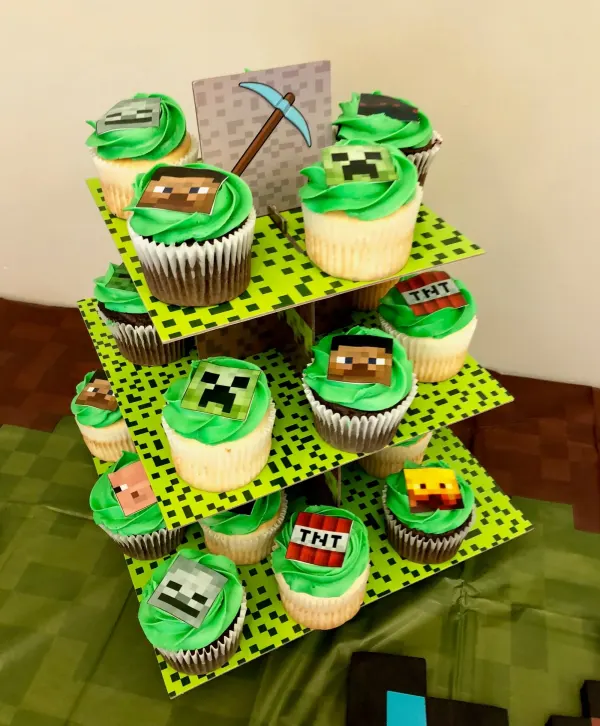 Three-tier stand of green frosted cupcakes with pixel Minecraft character and TNT toppers
