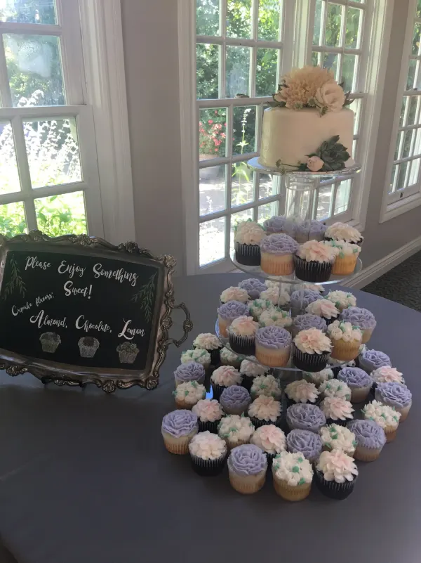 Cupcake tower in lavender and blush piped flowers with a small floral-topped cake and flavor sign