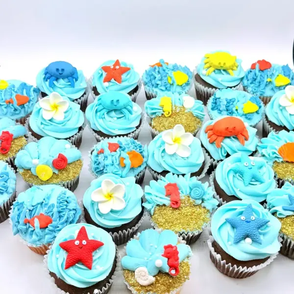 Ocean cupcakes in blue buttercream with fondant crabs, starfish, turtles and shells on sanded edges