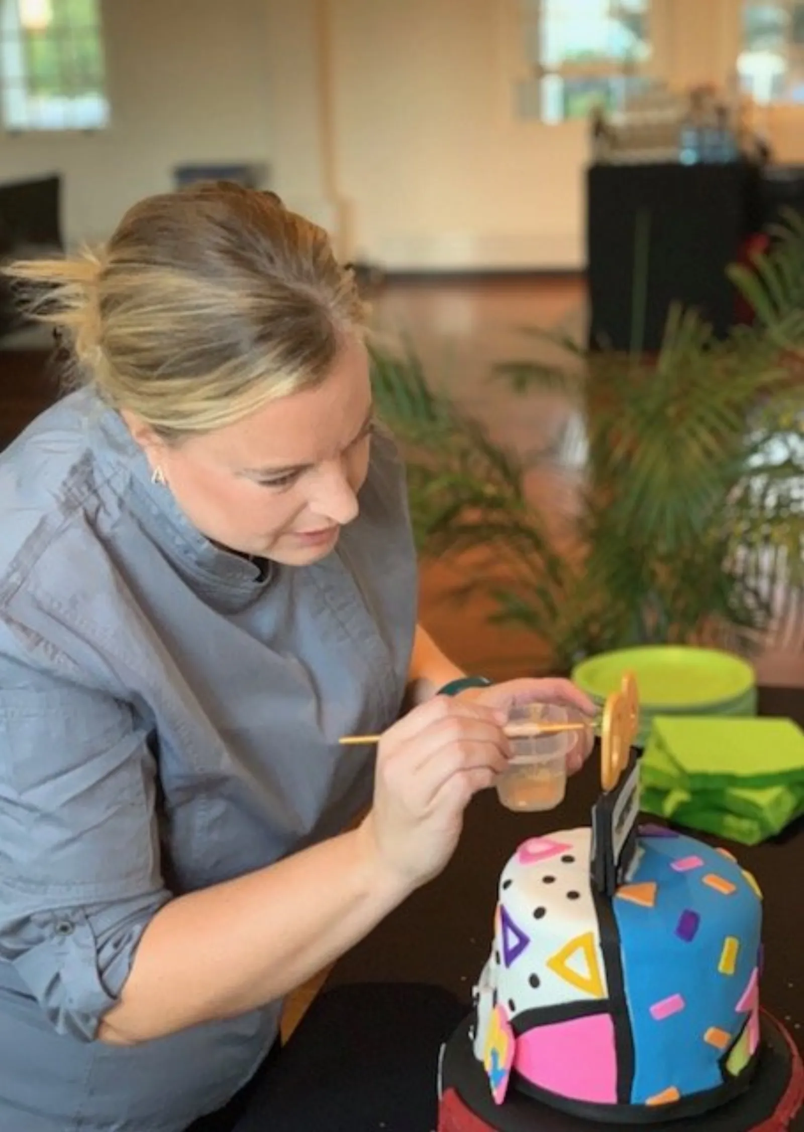 Lindsay Holdorf hand-painting a gold detail onto a brightly colored geometric birthday cake